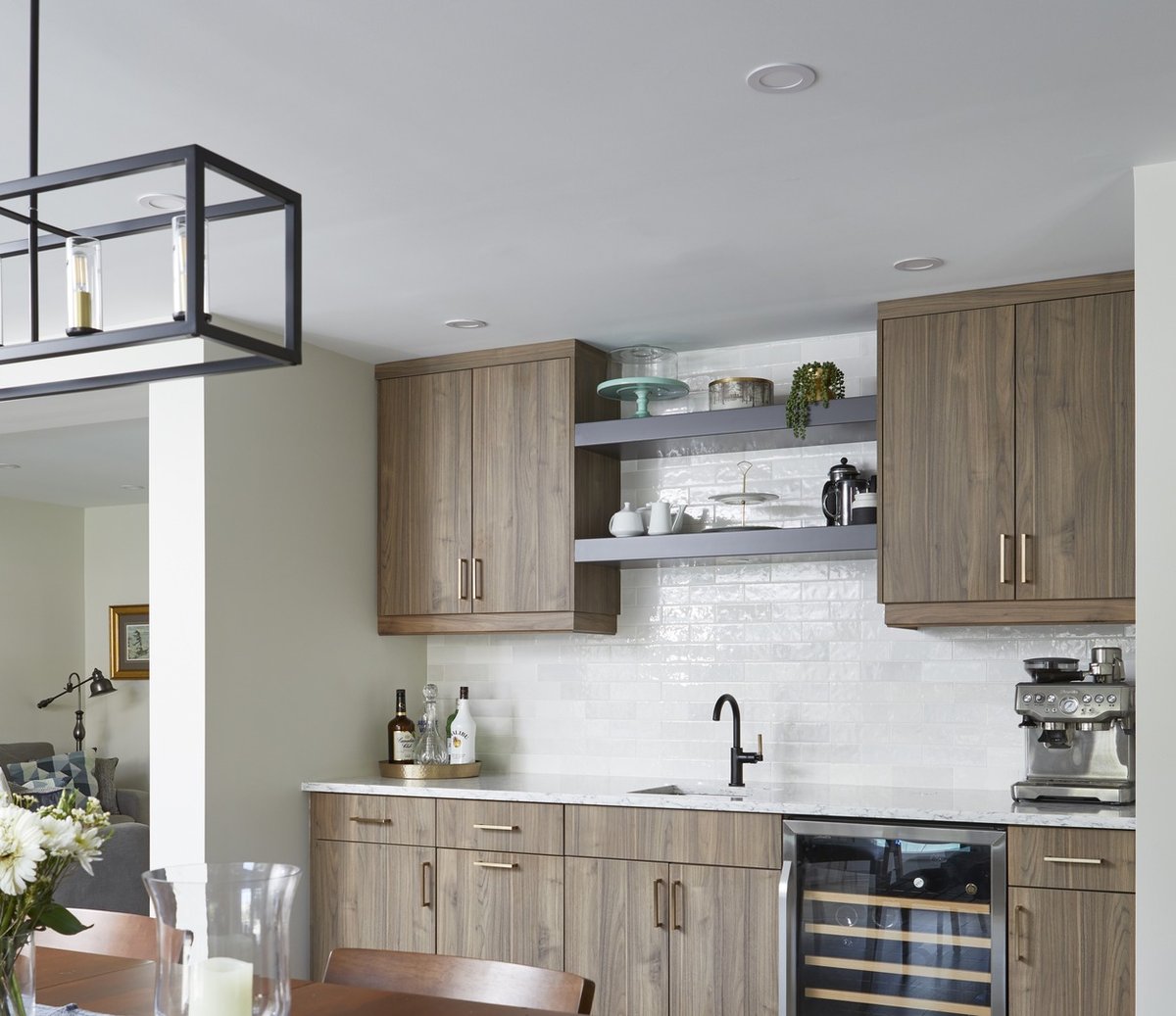 Beverage station area with built-in wine fridge and dining table view below pendant lighting