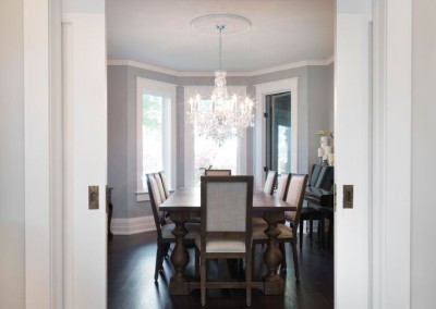 Transitional dining room with chandelier above table with sliding doors to entrance