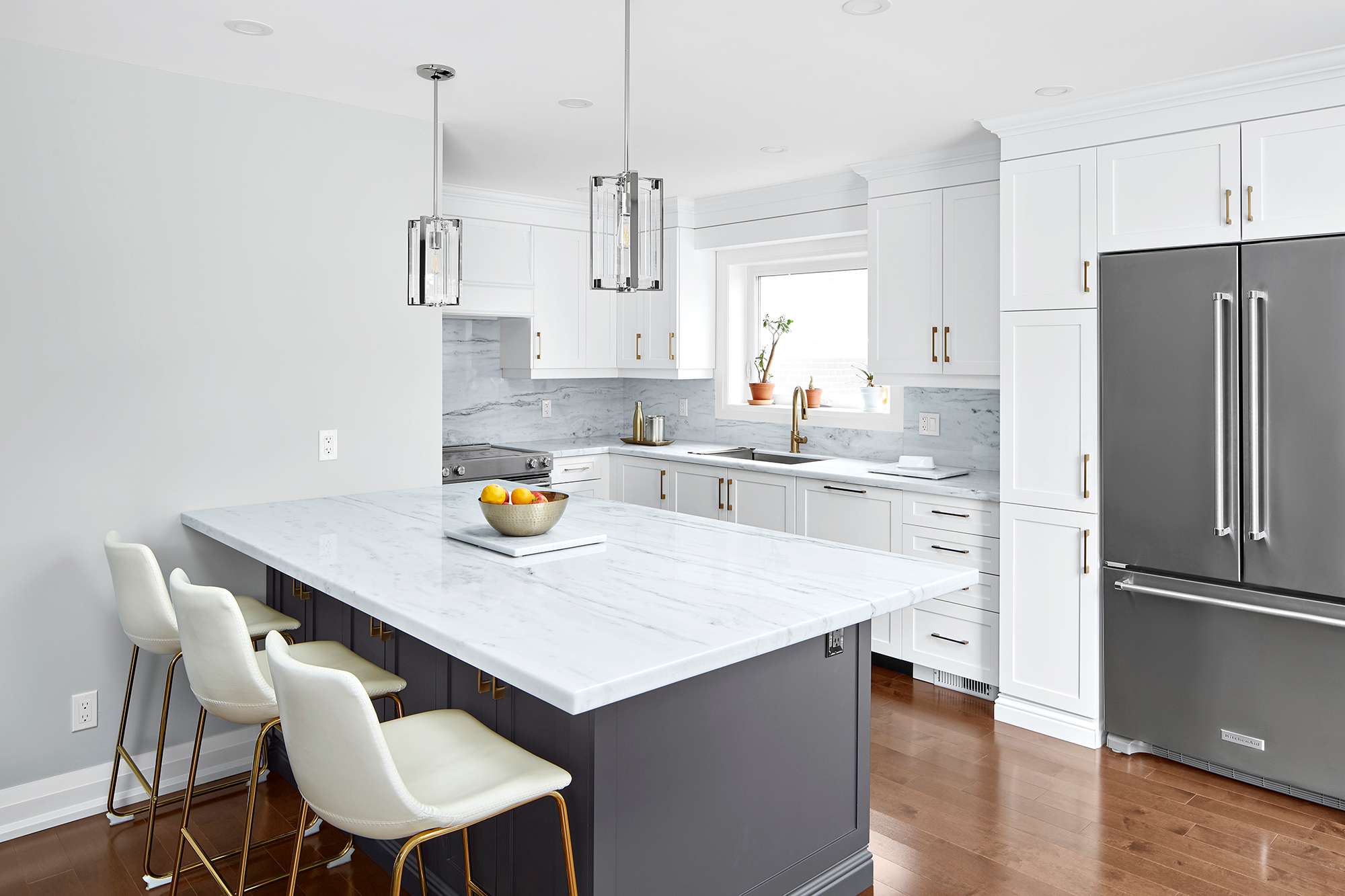 Three white chairs at island in white kitchen renovation in Markham by Master Edge Homes