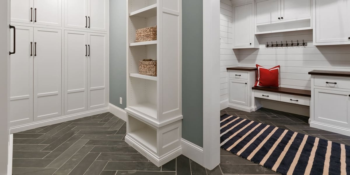 New and spacious mud room with herringbone tile flooring and white cabinets