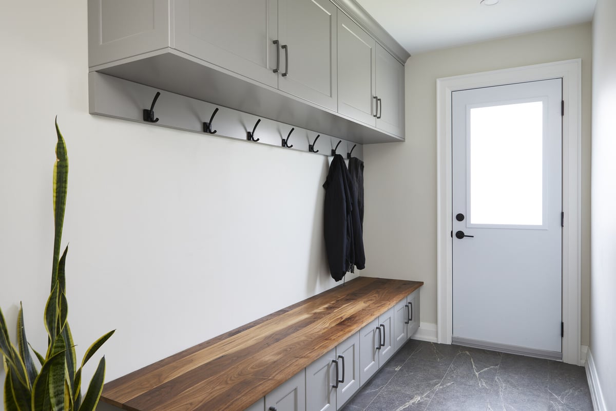 Renovated mudroom with built-in coat hooks and seating bench