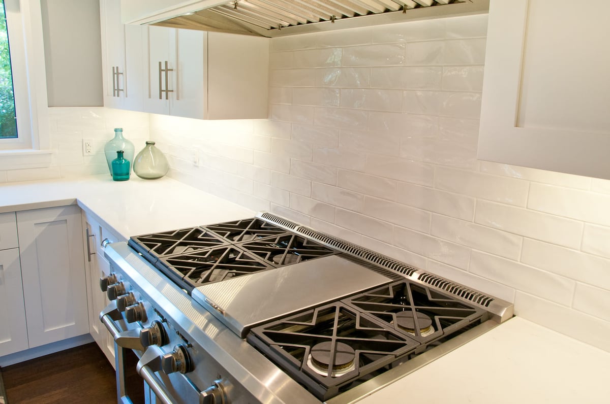 Stove top with white ceramic subway tile backsplash and under cabinet lighting in Markham