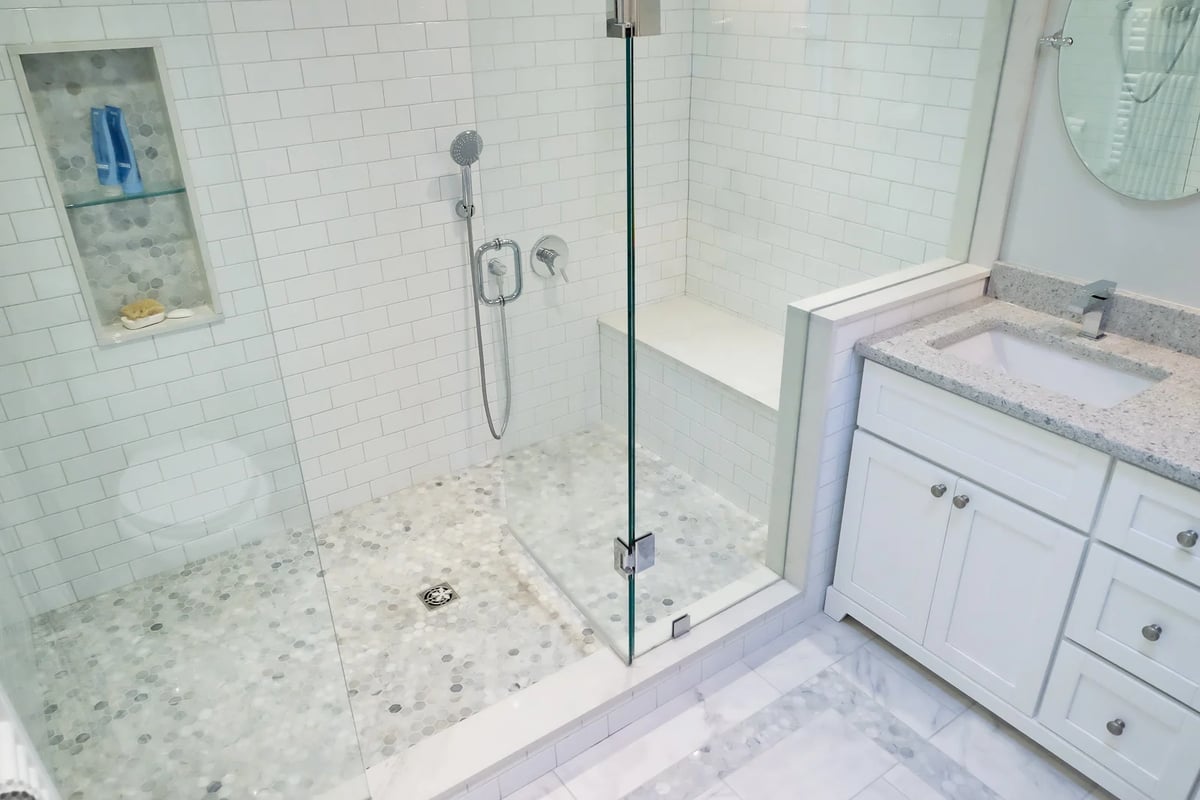 bathroom shower with bench seating and lower shower head handle and hexongonal tile in markham
