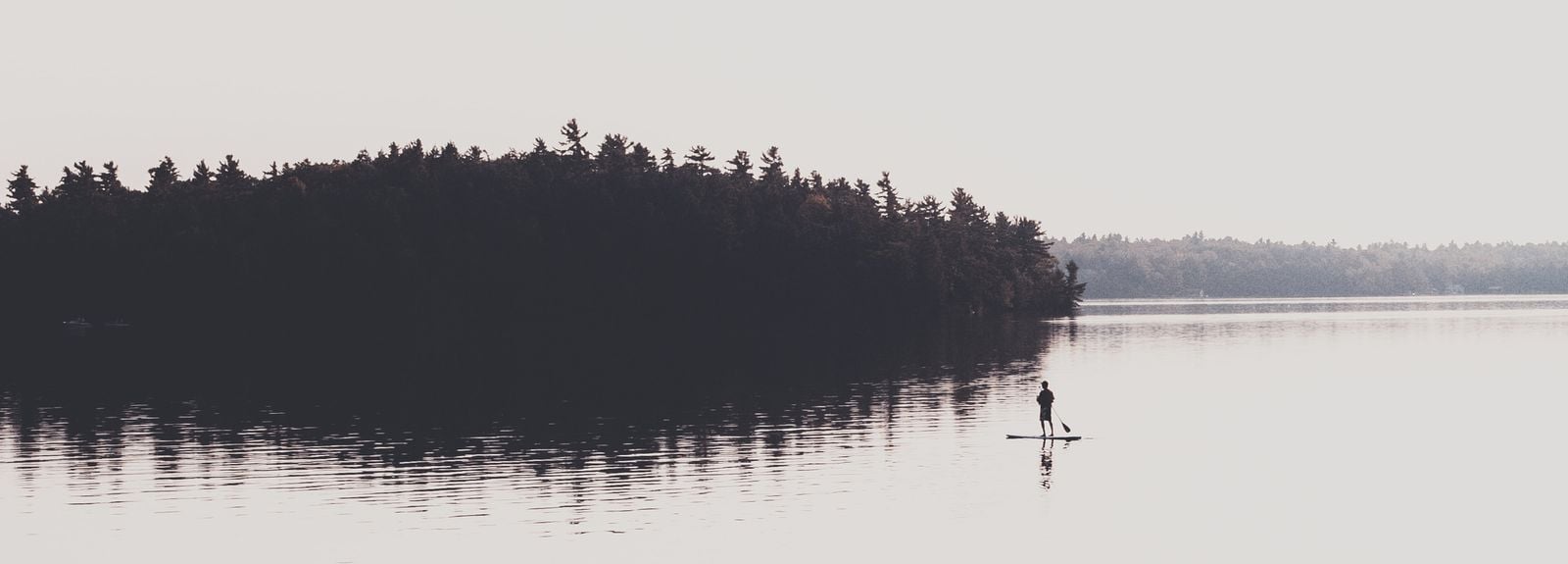 man in muskoka paddleboarding alone in the open water (1)