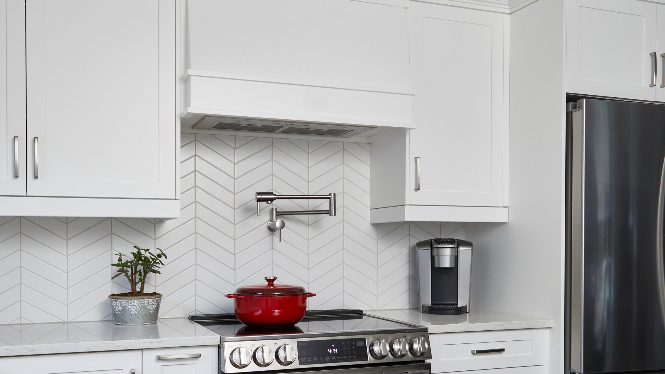 Modern white tile kitchen backsplash behind range hood