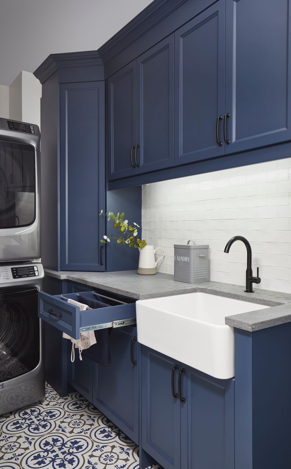 navy blue cabinets with open drawer towel drying hanger in clean and modern laundry room with mosaic tiling with undermount sink in markham ontario