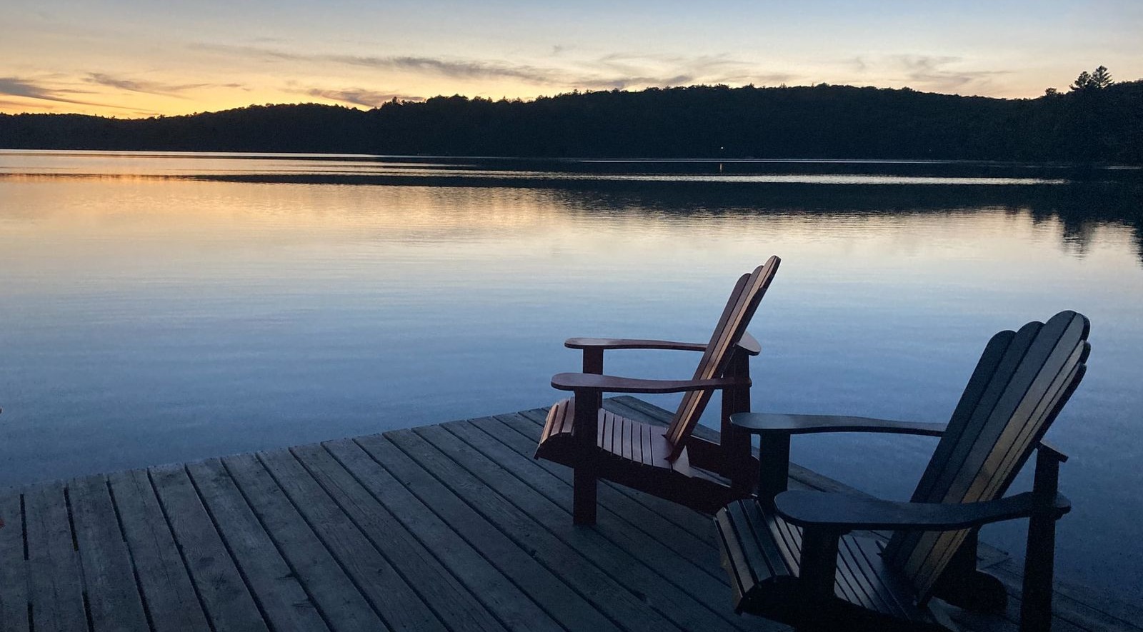 two Adirondack Chairs next to lake with gorgeous sunset in muskoka ontario (1)