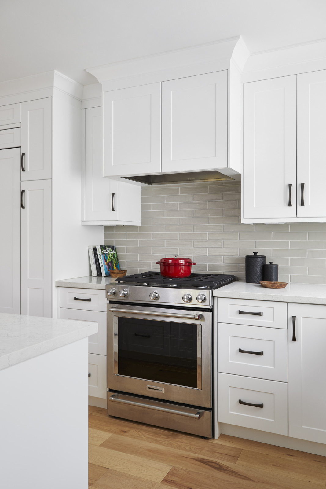 white modern kitchen renovation with gas KitchenAid oven grey tiled backsplash and red pot in Markham