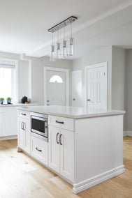 white modern kitchen renovation with white kitchen island and microwave in island in markham