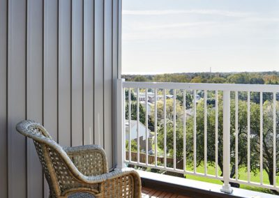 Raised deck attached to home with chair and white railing Raised deck attached to home with chair and white railing
